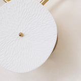 Close view of one ceramic disc, its surface pressed with a petal texture