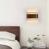 Sconce lit above a bed beside a nightstand with two small glass vases