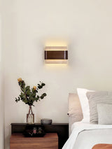 Sconce lit beside a bed above a nightstand holding a small green plant