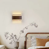 Sconce lit above a bed with ochre cushions and a woven headboard