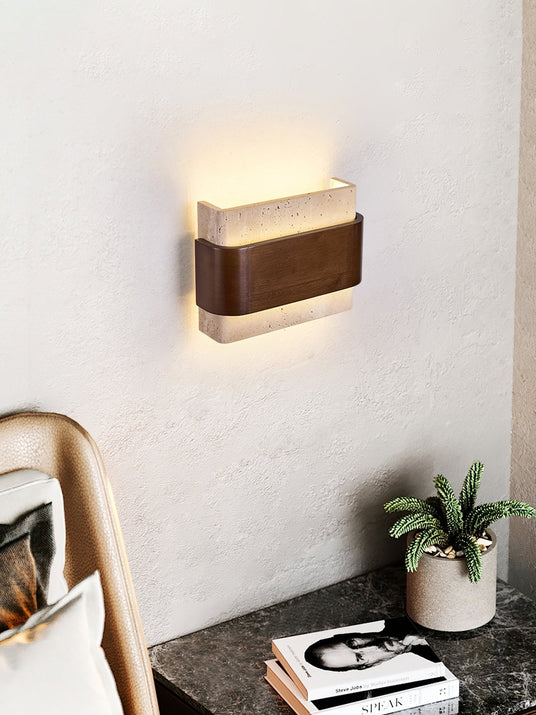 Sconce lit above a bedside table with a record player and a plant