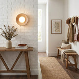 Sconce lit on a brick entry wall above a console with a bench and hooks