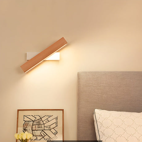 Sconce lit above a bed beside an upholstered headboard and a framed print