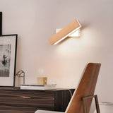 Sconce lit above a dark console with framed prints and a wood chair below