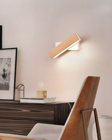Sconce lit above a console beside a wood chair and two leaning frames