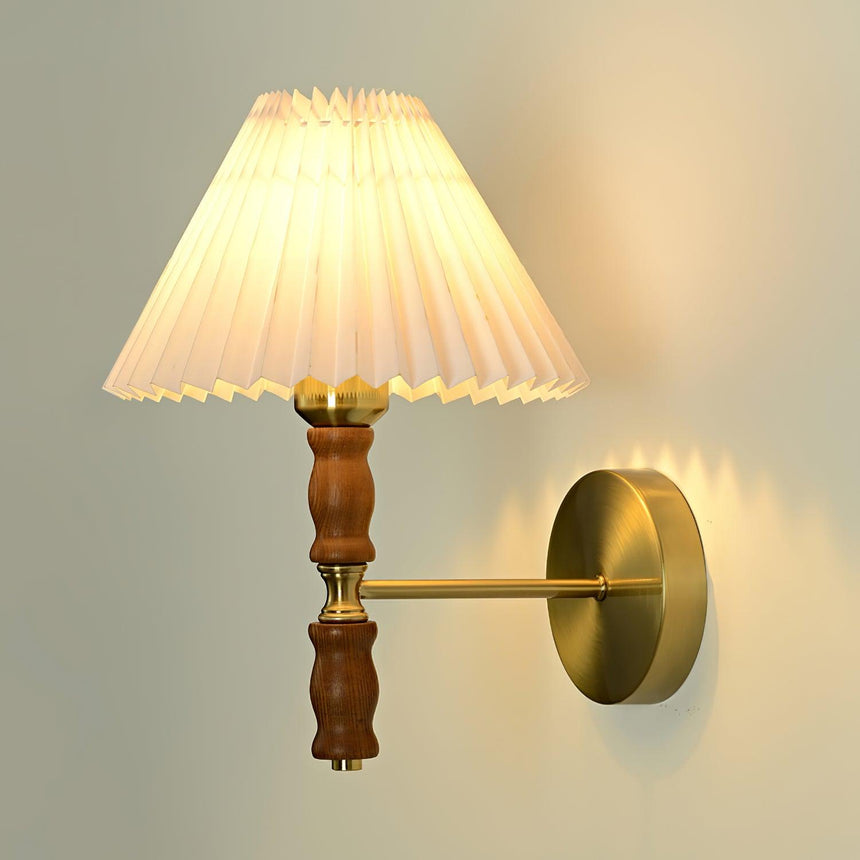 Pleated shade lit, seen from the side with the brass arm and wall plate
