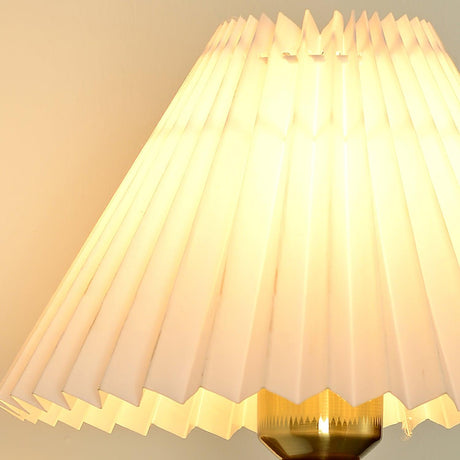 The pleats of the fabric shade seen close up, warm light behind them