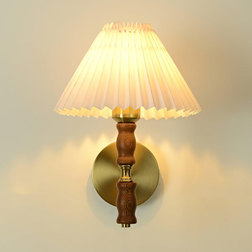 Pleated white shade lit above a turned walnut column and brass arm