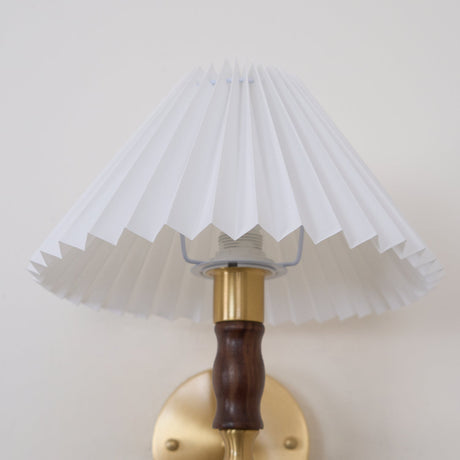 Pleated shade and walnut column seen unlit against a plain background