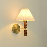 Warm light through a pleated linen shade on a walnut and brass sconce