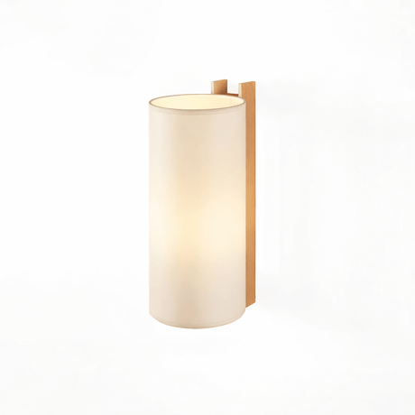 The tall fabric shade lit from within, the wood post rising behind it