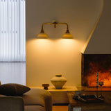 The double sconce lit above a fireplace wall, a low table and a ceramic vase below