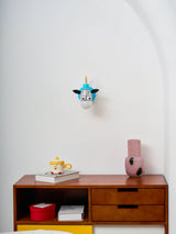 The zebra lamp on a white wall above a wood dresser and a vase