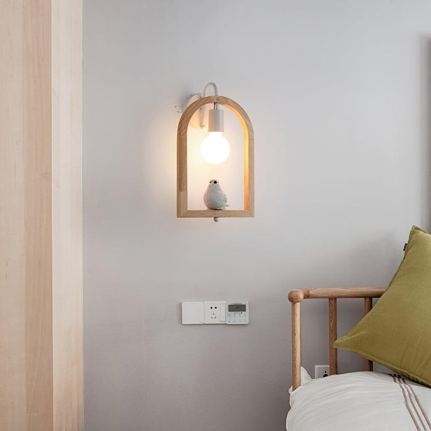 Sconce lit beside a bed with a green cushion and a wood chair nearby