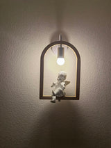 The winged figure lit on a dark wall, a soft halo around the globe