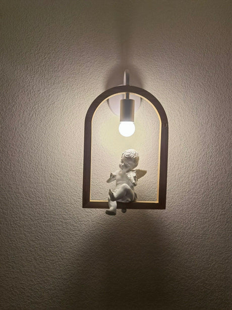 The winged figure lit on a dark wall, a soft halo around the globe