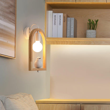 Sconce lit beside shelving with books and a plant above a pale bench