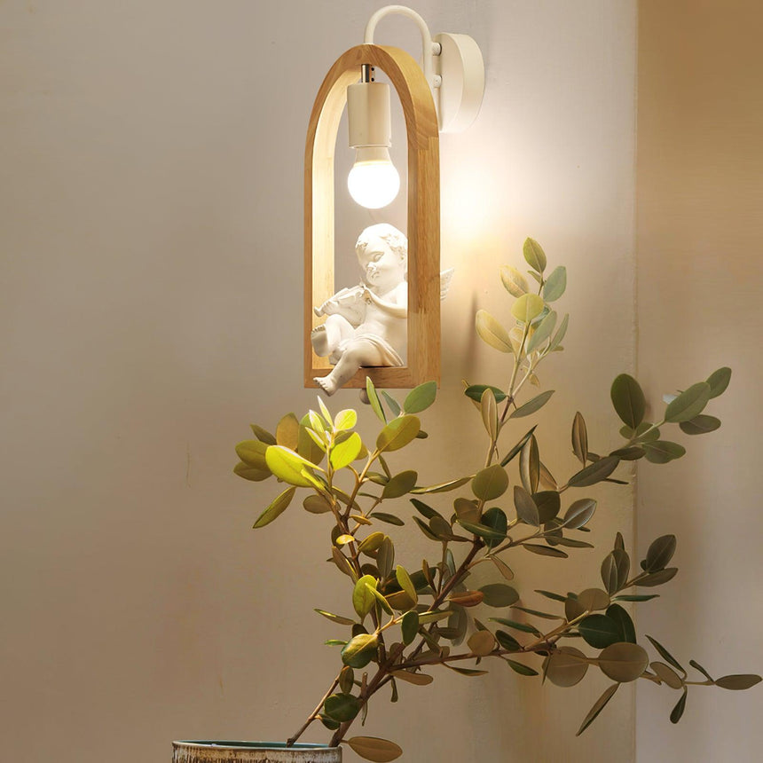 Sconce lit beside a branch of green foliage set against a pale wall