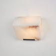 A single alabaster block lit on a plain wall, a rust vein across the front