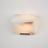 A single alabaster block lit on a plain wall, a rust vein across the front
