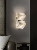 Two stepped blocks lit on a dark wall above a leather chair and a cushion
