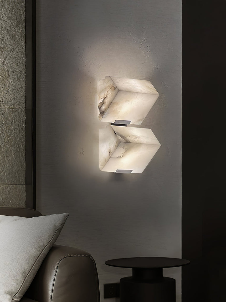 Two stepped blocks lit on a dark wall above a leather chair and a cushion
