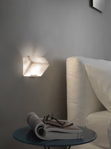 A single block lit on a gray wall above a sofa arm and a round side table