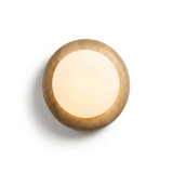 The globe lit inside the cushioned wood disk, the grain warm around it