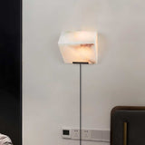The single block lamp on a wall above an outlet, its cord running to the plug