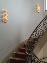 Stepped alabaster lamps on the curved wall of a spiral staircase with an iron rail