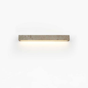 The shorter bar lit on a pale wall, the light pooling softly under the stone