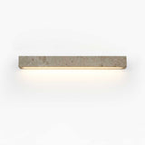 The longer bar lit on a pale wall, a wide even wash below the stone block