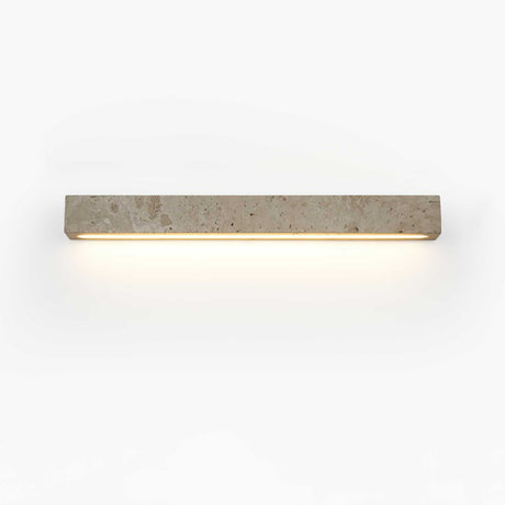 The longer bar lit on a pale wall, a wide even wash below the stone block