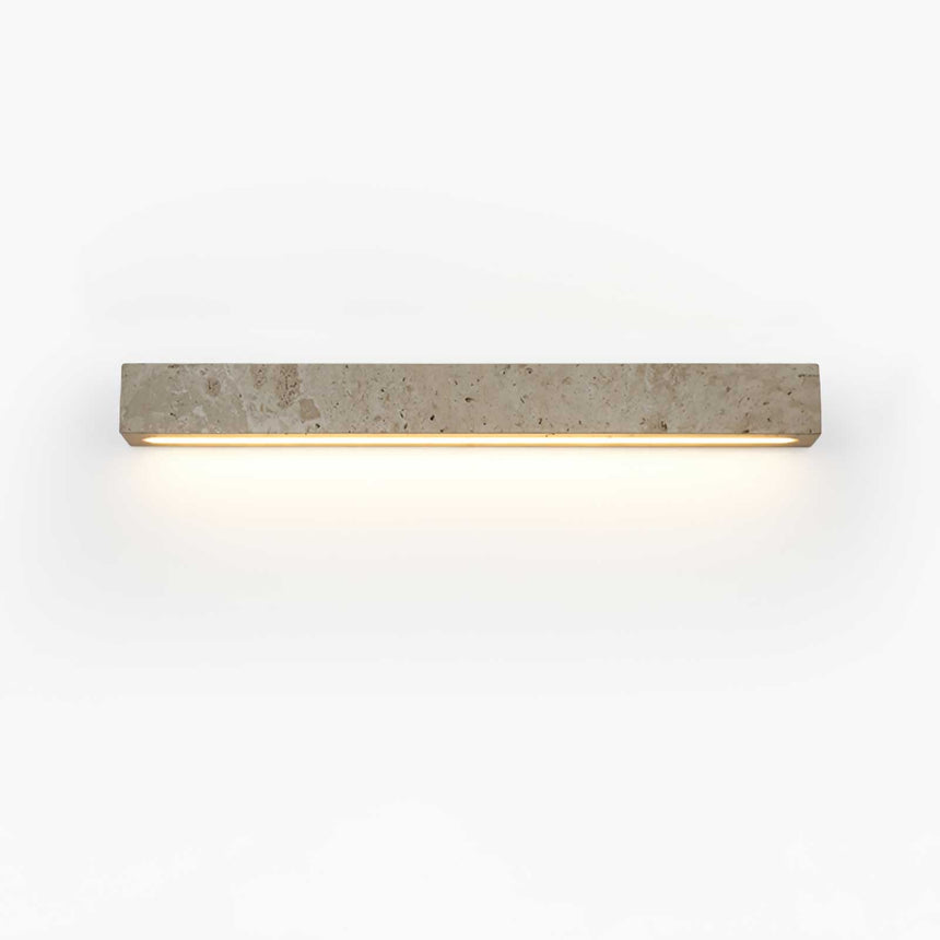 The longer bar lit on a pale wall, a wide even wash below the stone block