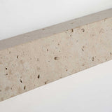Close view of the travertine face, its open pores and pale banding across the block