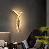 The sconce lit on a dark wall above a black armchair and a side table