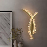 The crossed arms lit above a console with a vase of dried grasses and framed art