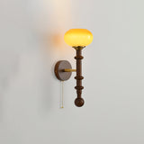 Amber glass shade lit warm at the top of a tall walnut column