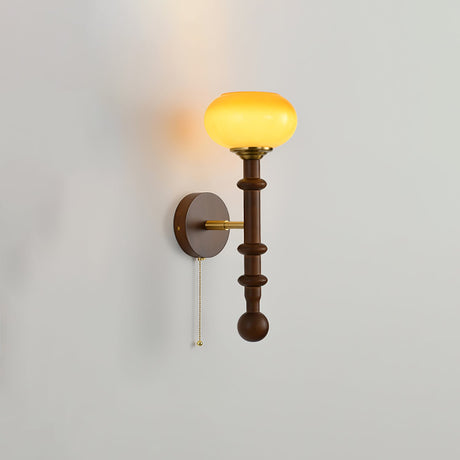 Amber glass shade lit warm at the top of a tall walnut column