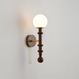 White glass globe lit above a walnut column and a round wall plate