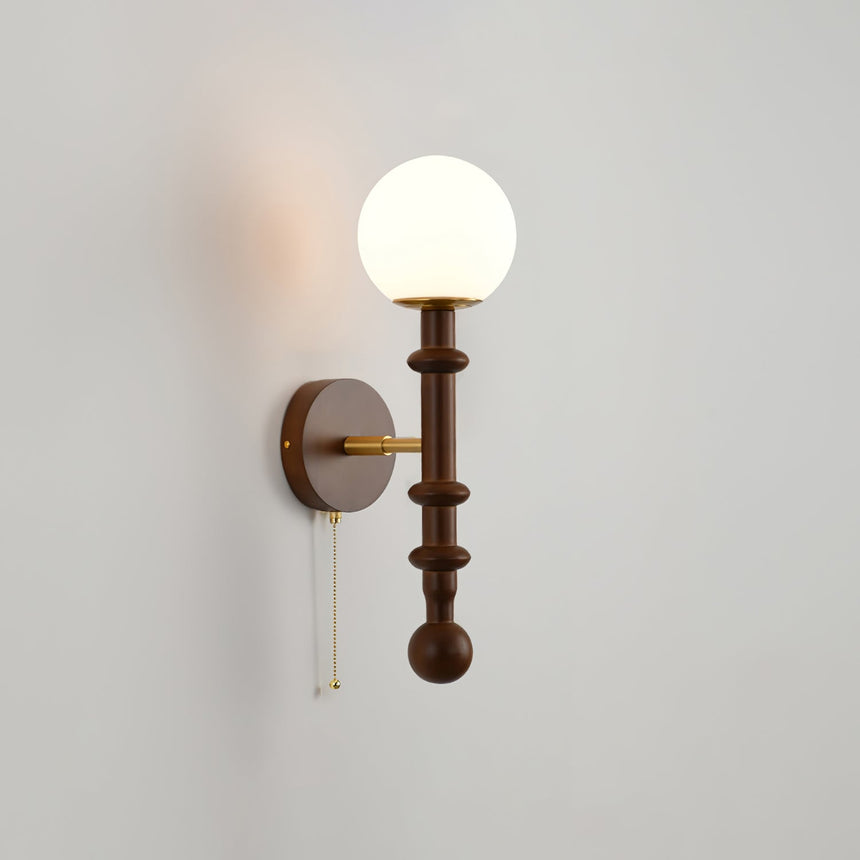 White glass globe lit above a walnut column and a round wall plate