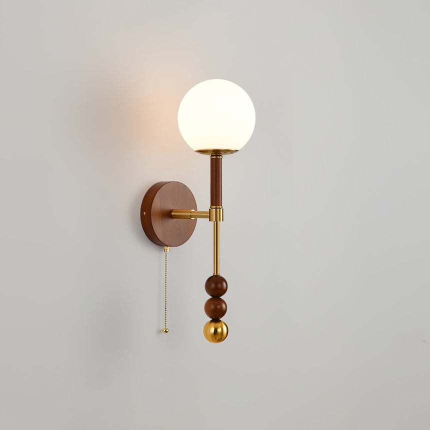White globe shade unlit on a walnut column, photographed on a plain wall