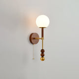 White glass globe on a walnut column, seen straight on against a pale wall