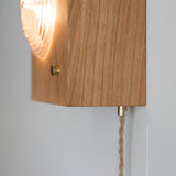 The square wood box seen from the side with the brass knob on its face