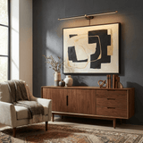 Slim rod lit on a dark painted wall above a framed artwork and a walnut sideboard