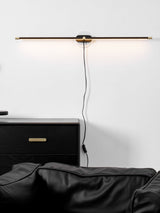 Rod lit above a black drawer unit and a leather chair, the cord loose on the wall