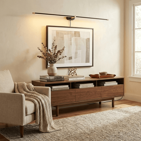 Slim rod lit above a framed print over a long walnut console with books and a vase