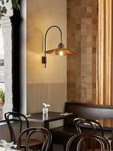 Sconce lit above a marble table with bentwood chairs and a tiled wall