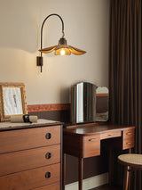 Sconce lit above a chest of drawers with a dressing mirror and a frame