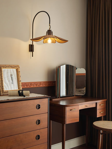 Sconce lit above a chest of drawers with a dressing mirror and a frame